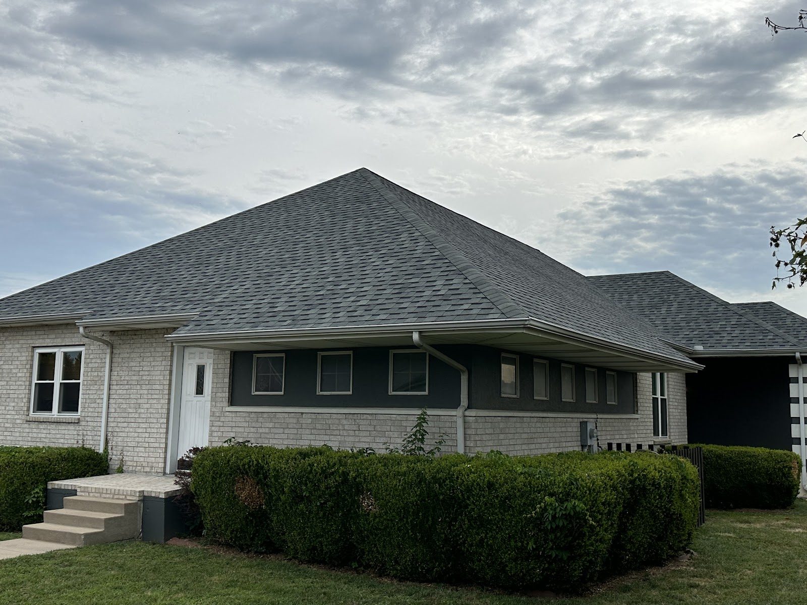 A brick house with a new gray shingle roof