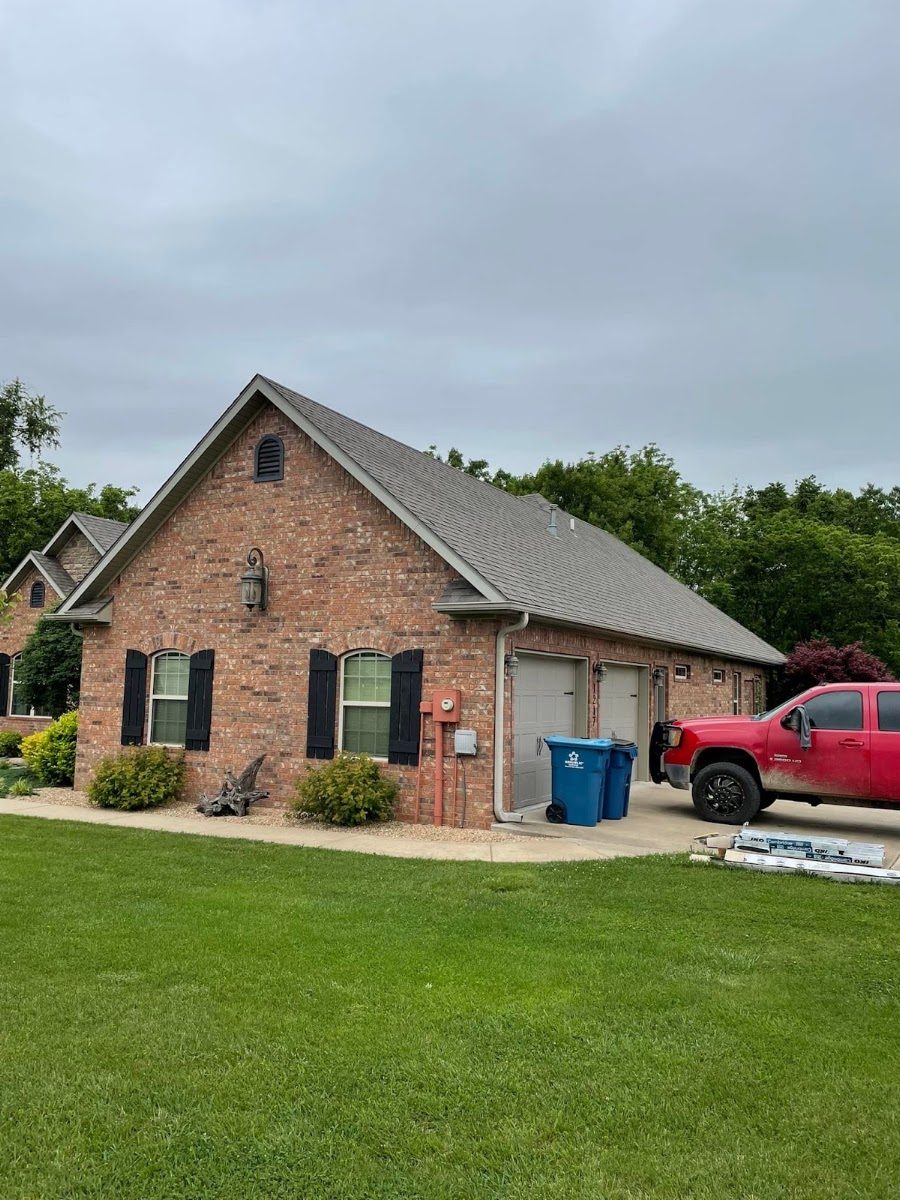A red brick house with a new roof and a two-car garage